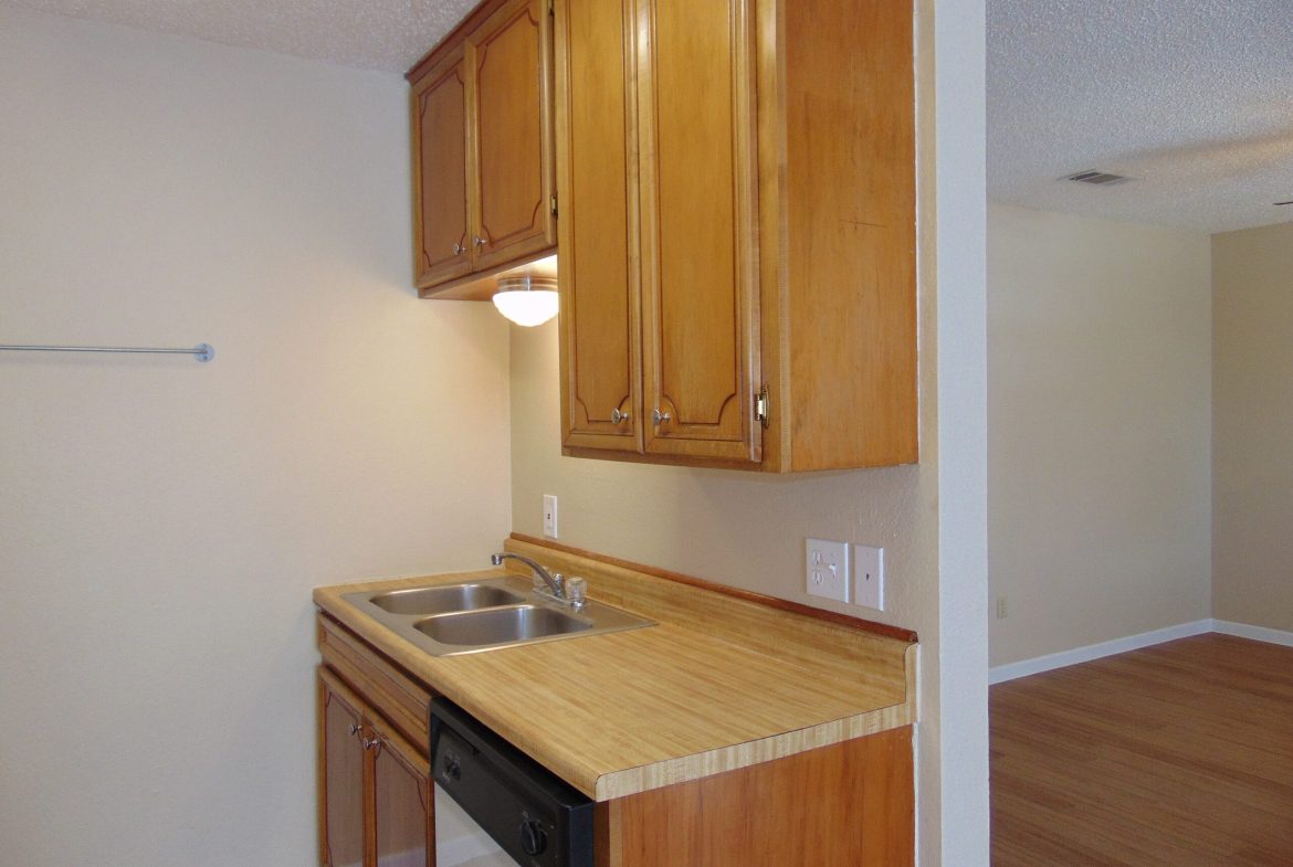 Apartment kitchen with wood cabinets and sink.