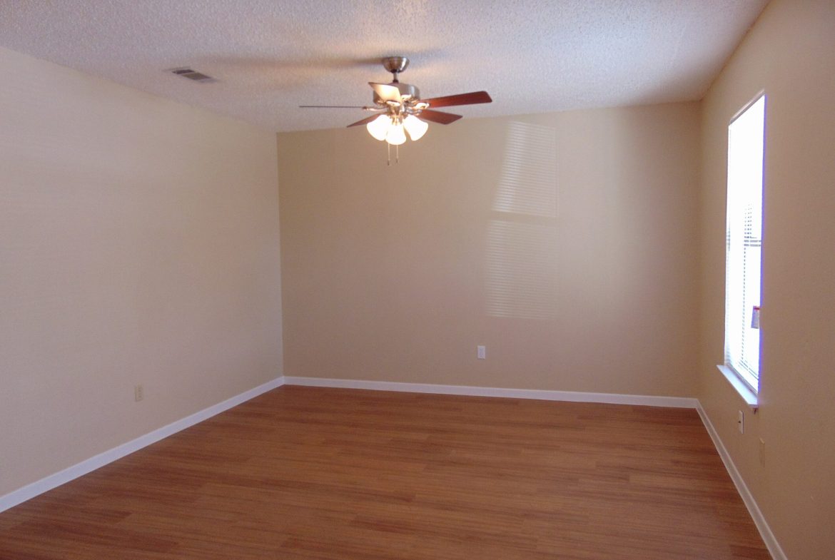 Empty room with wood floor and fan.