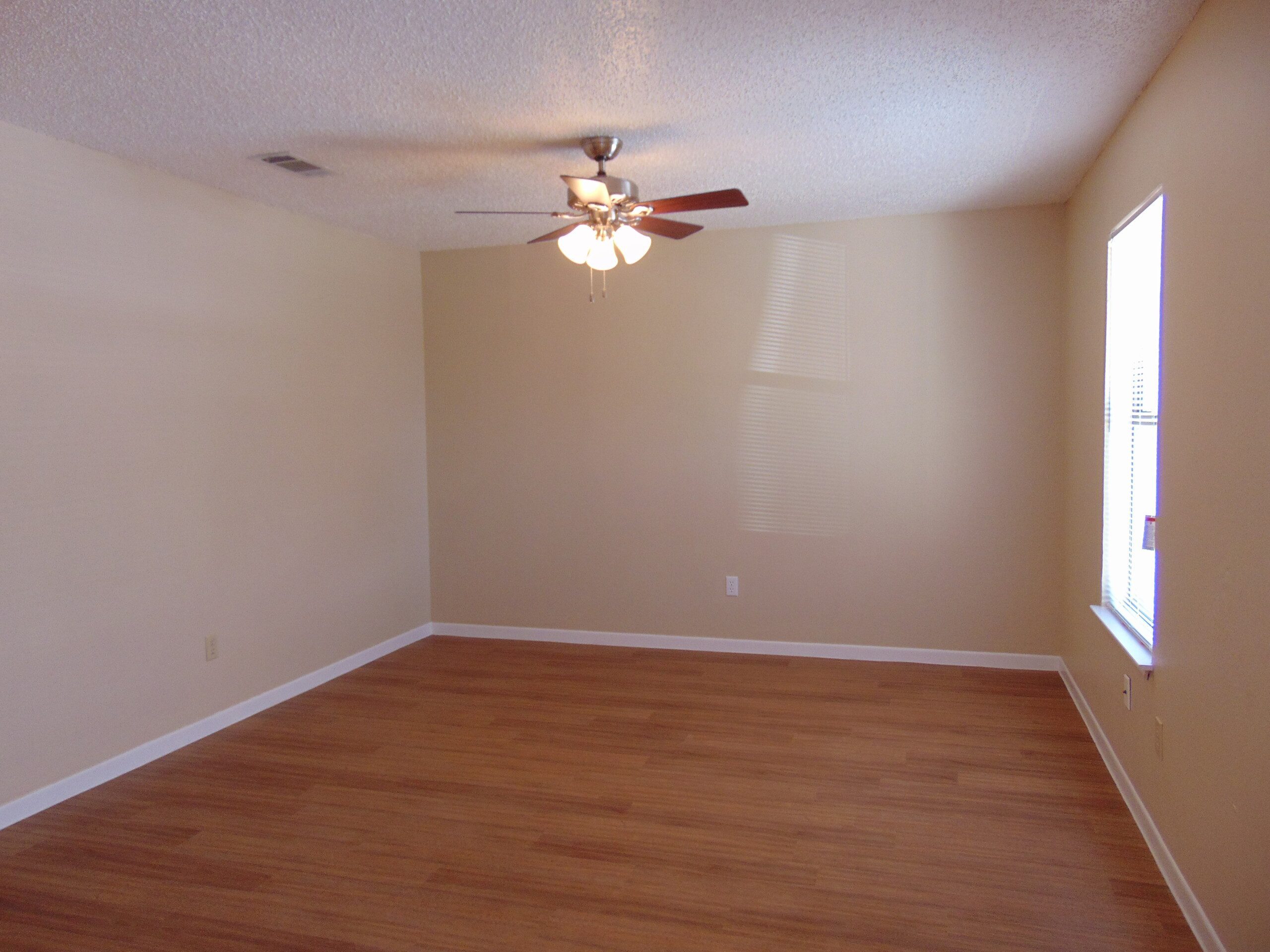 Empty room with wood floor and fan.