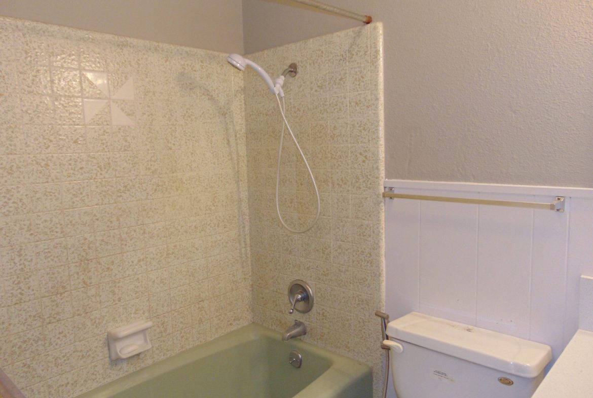 Green bathtub, beige tile, white toilet.