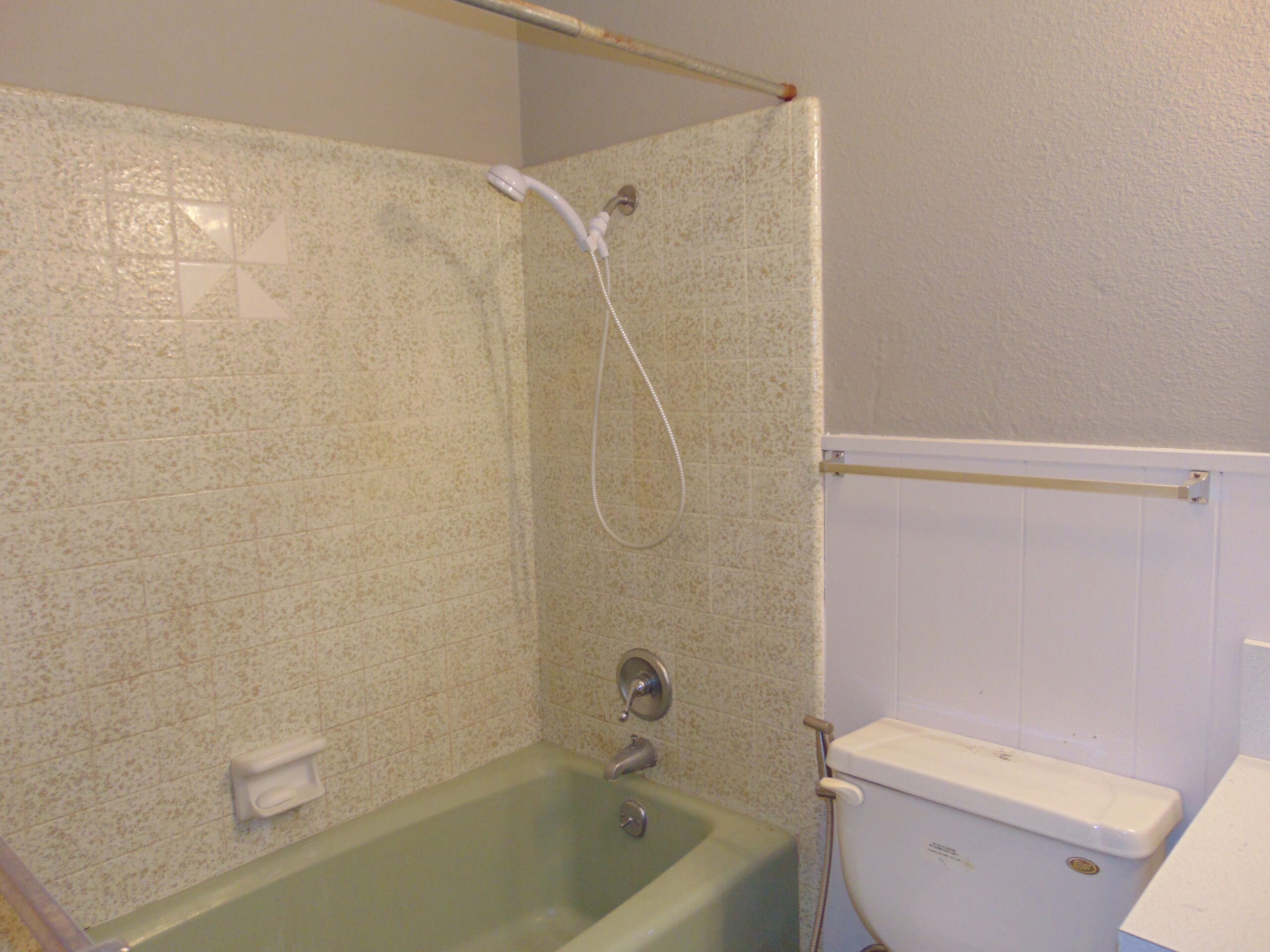 Green bathtub, beige tile, white toilet.