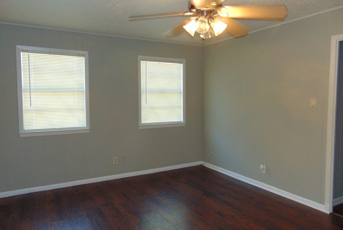 Empty bedroom with dark wood floors.