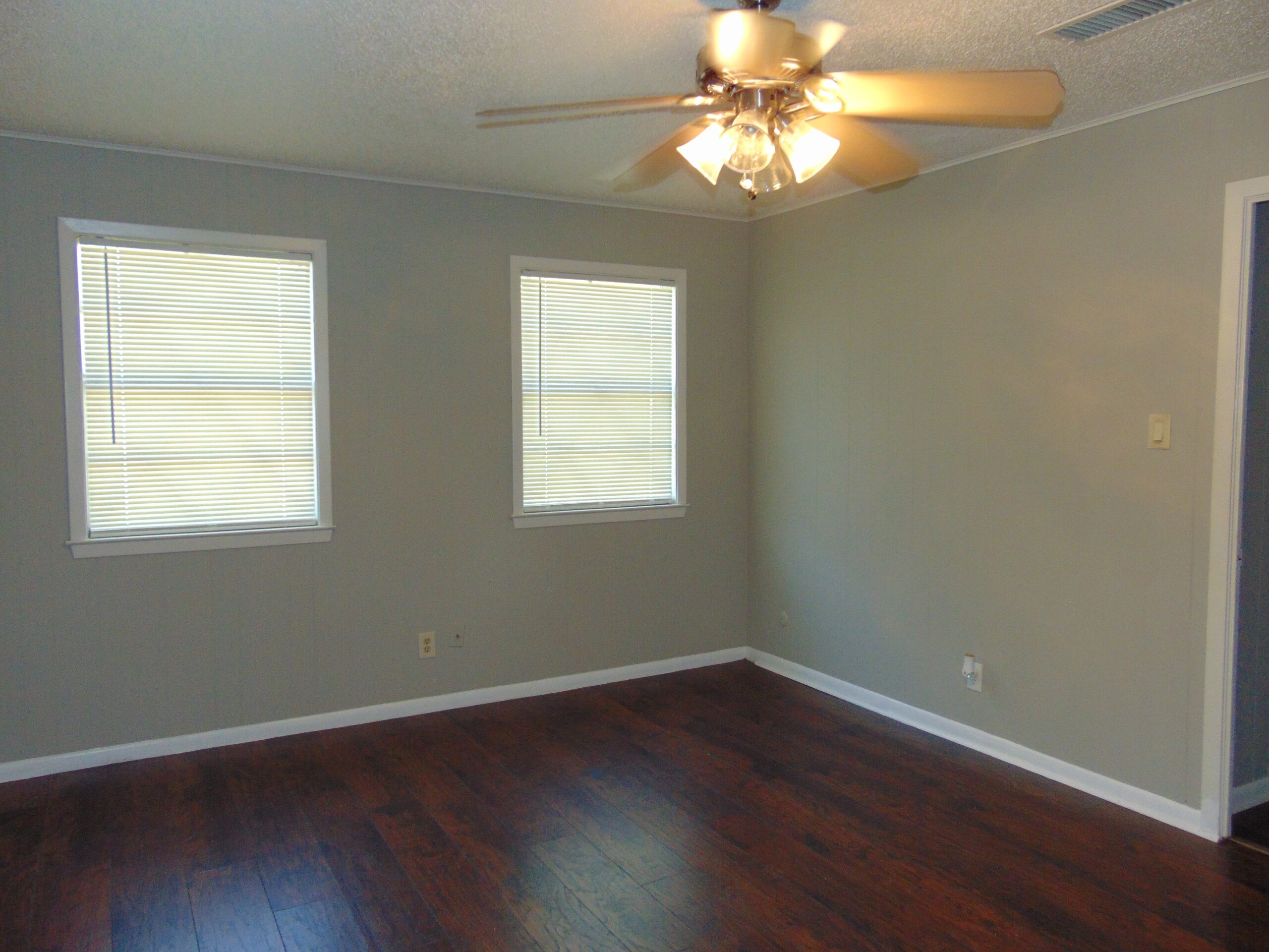 Empty bedroom with dark wood floors.