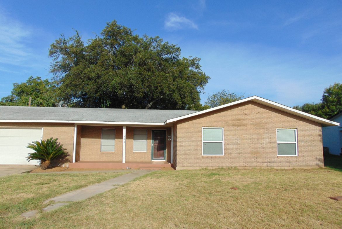 Brick ranch house with yard and tree.