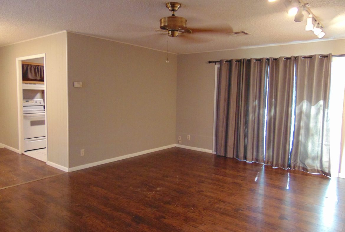 Empty room with hardwood floors and curtains.