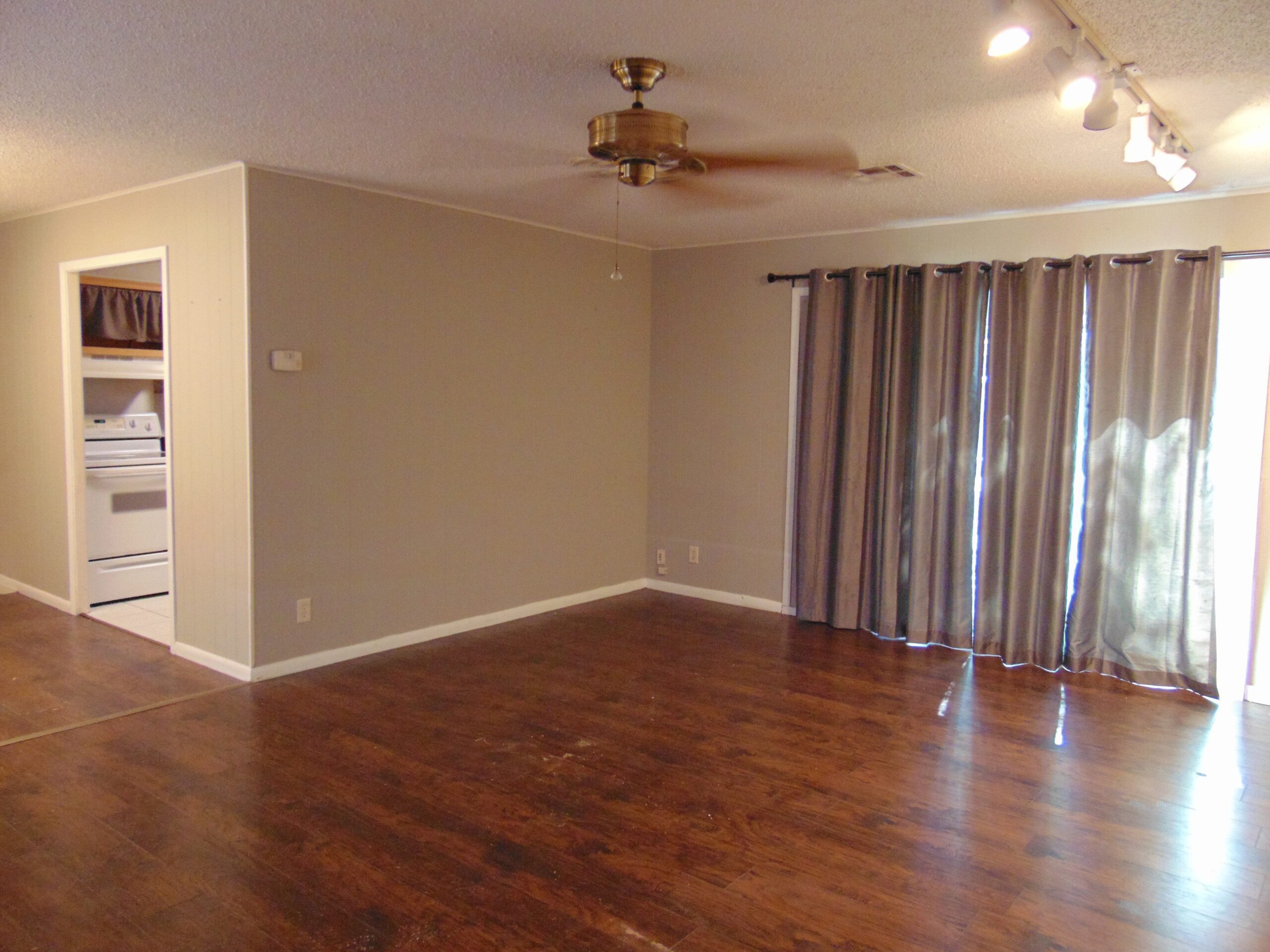 Empty room with hardwood floors and curtains.