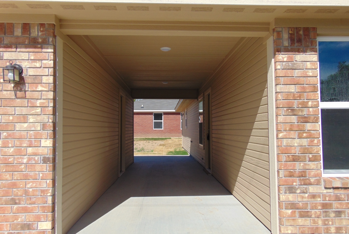 Covered walkway to brick house.