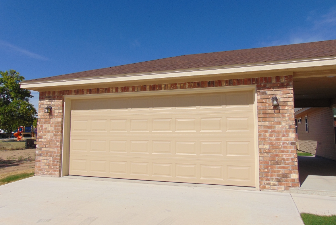 Beige garage door on brick house.