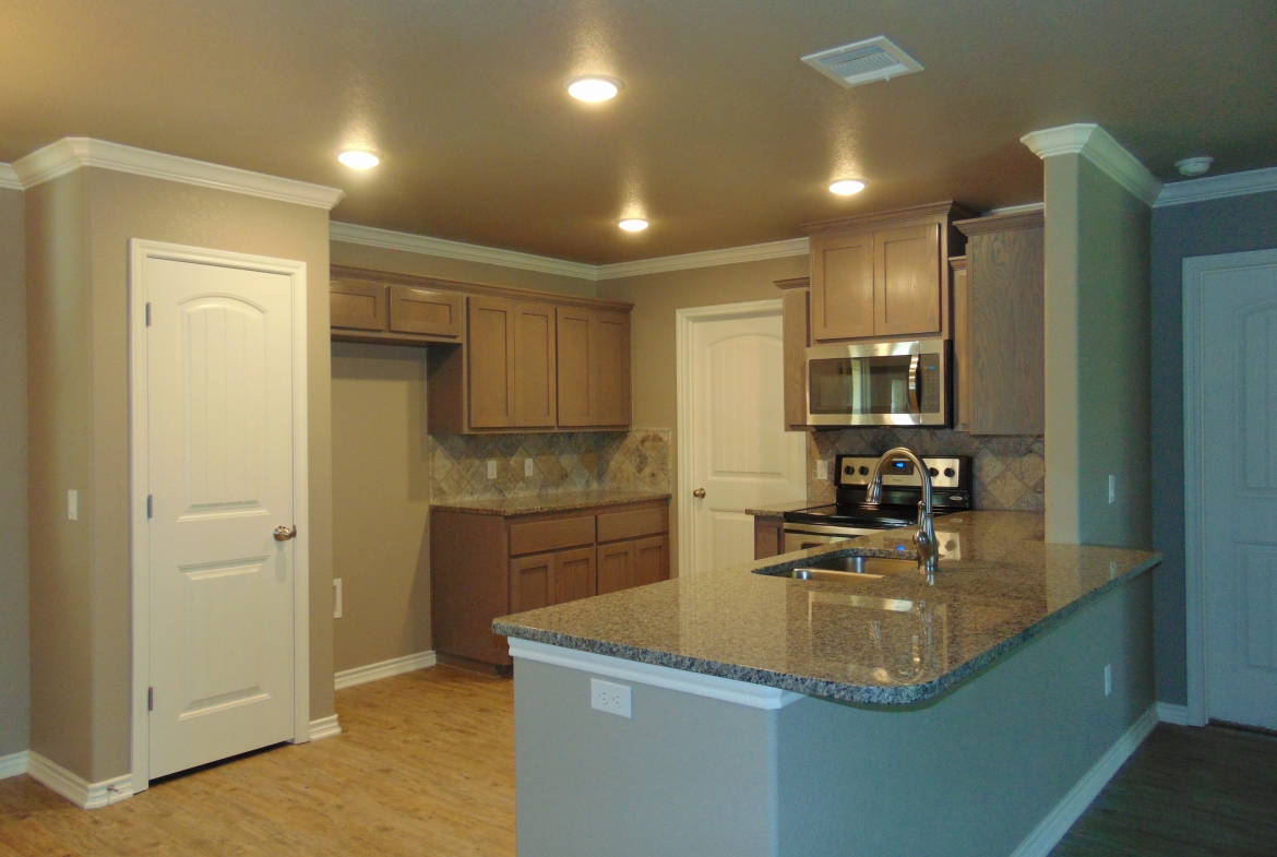 New kitchen with granite countertops and wood cabinets.