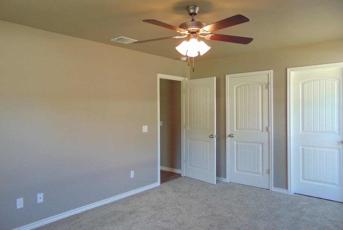 Empty bedroom with ceiling fan and doors.