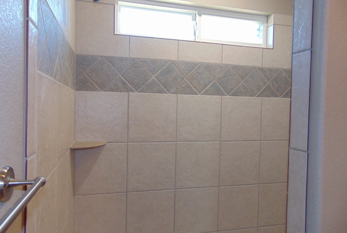 Beige tiled shower with window.