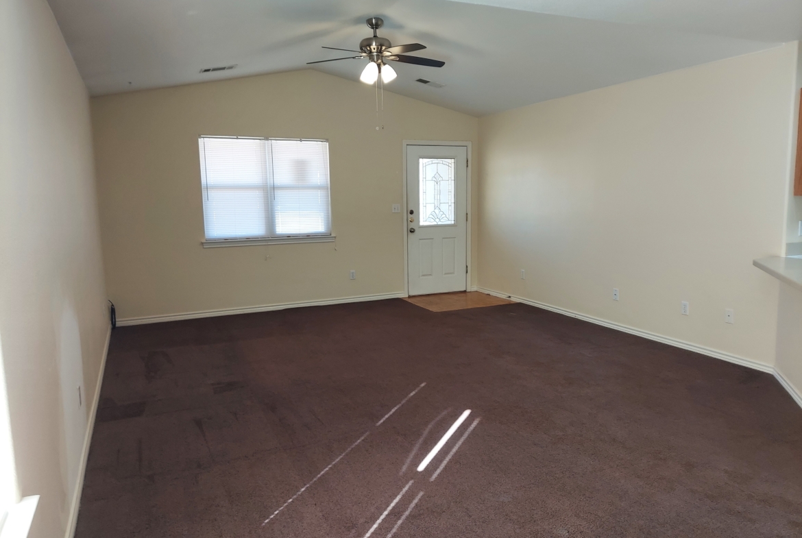 Empty room with brown carpet and ceiling fan.