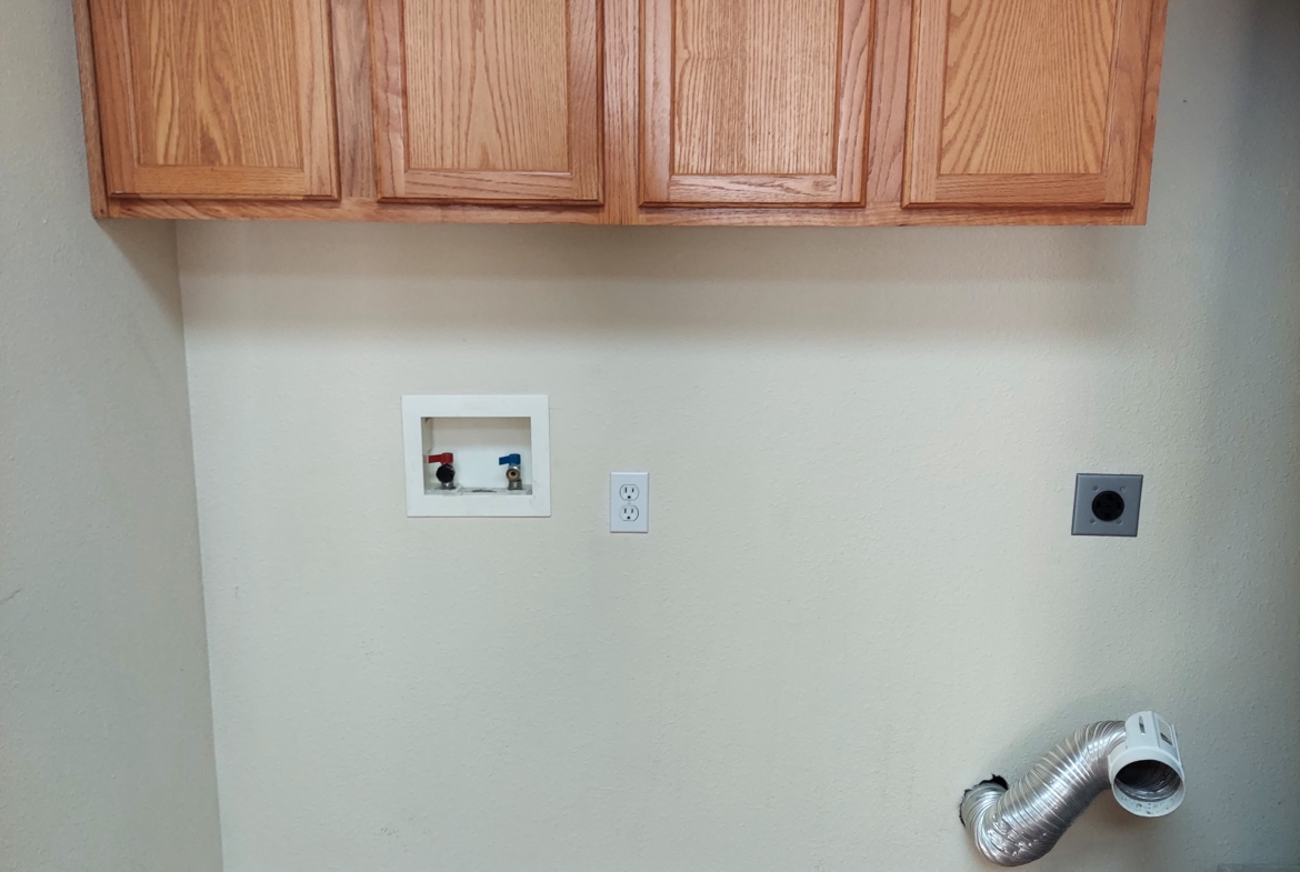 Unfinished laundry room with cabinets.