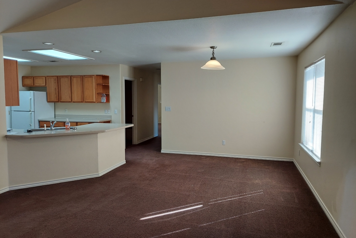 Empty apartment living room with kitchen view.