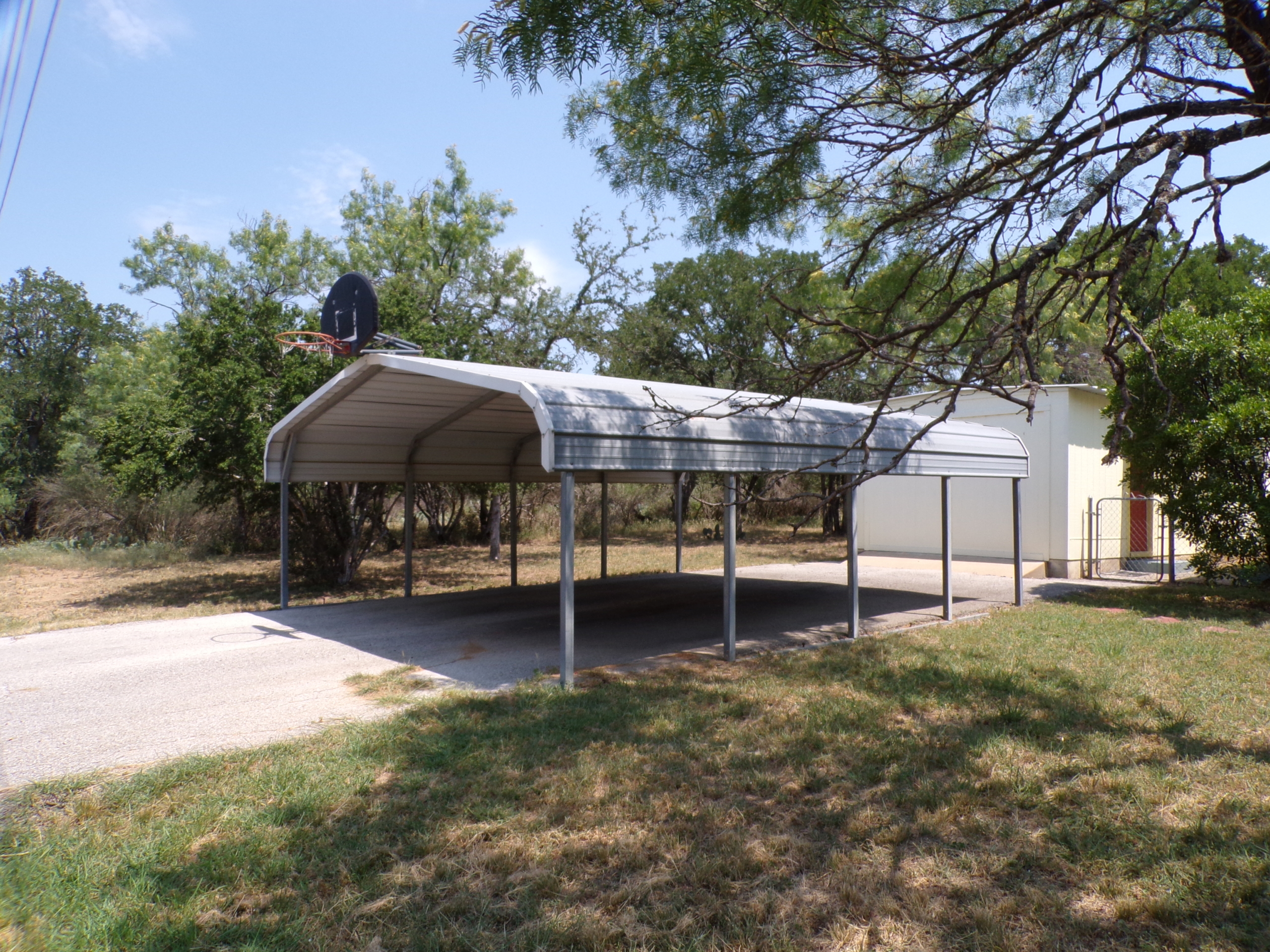 Metal carport with basketball hoop.