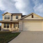 Beige two-story house with attached garage.