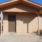 Here's an alt tag for the image: `Brick house with covered porch and door`