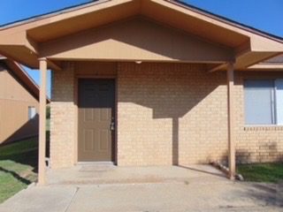 Here's an alt tag for the image: `Brick house with covered porch and door`