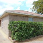 Brick building, number 402, green hedge.