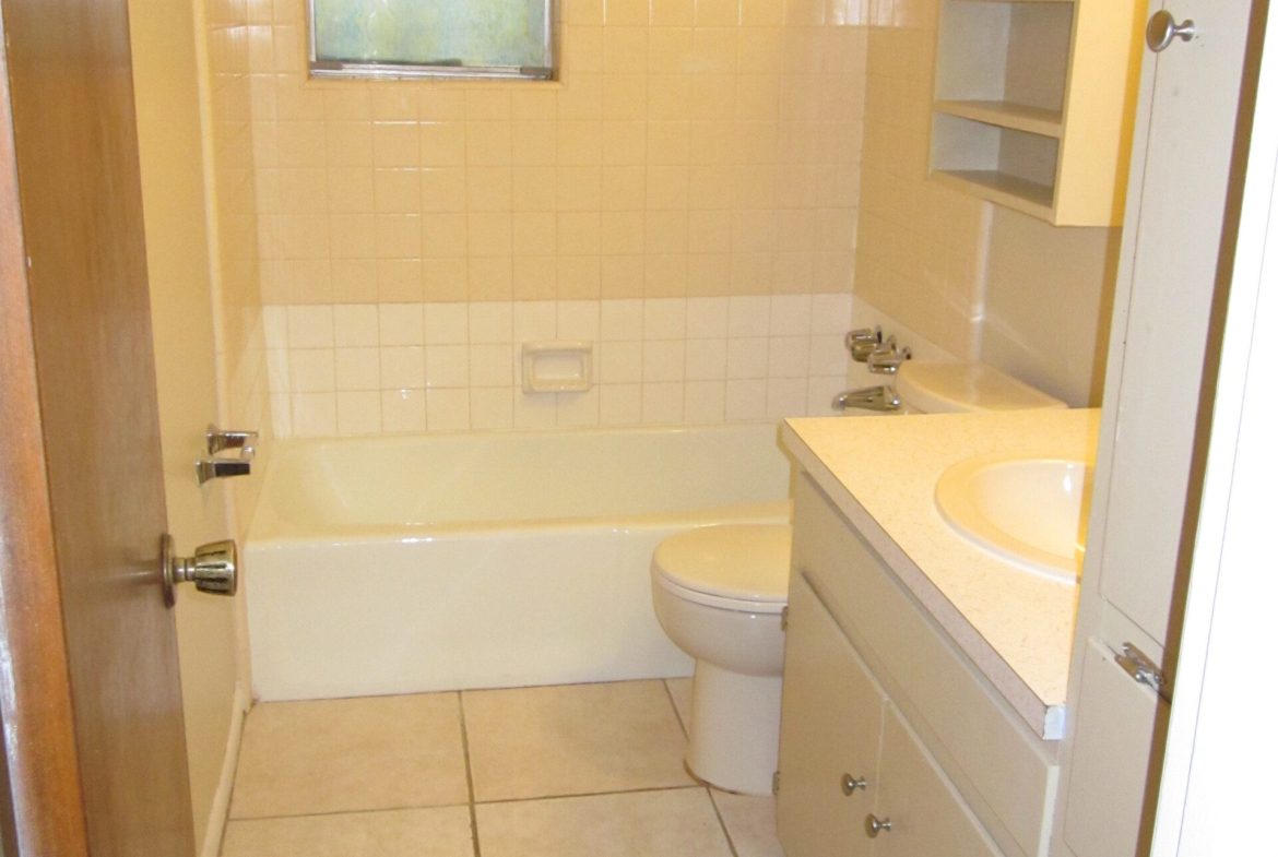 Beige bathroom with tub, toilet, and sink.