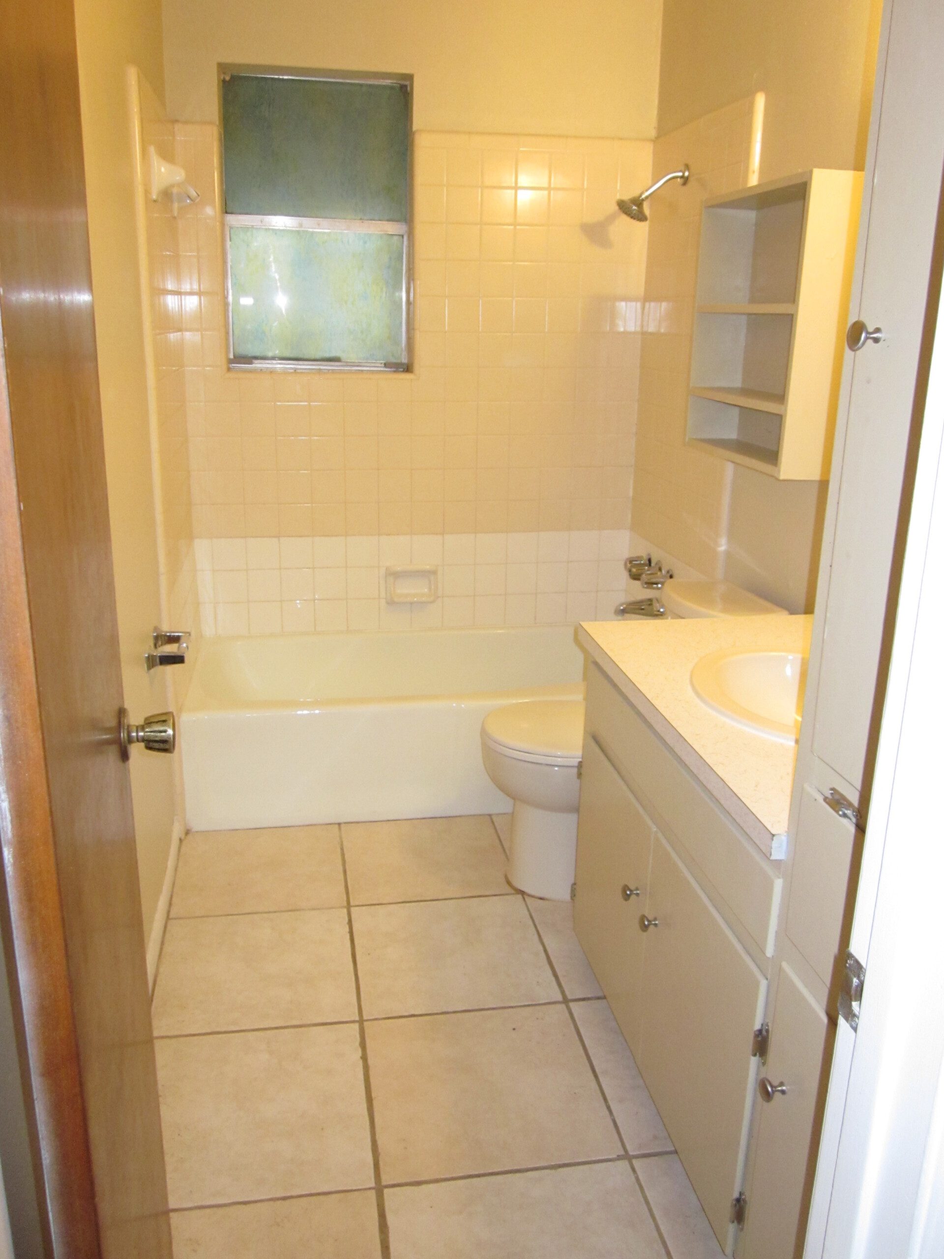 Beige bathroom with tub, toilet, and sink.