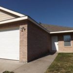 Here's an alt tag for the image: Brick duplex with attached garage.