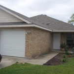 Tan brick house with attached garage.
