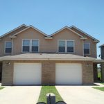 Tan duplex with attached garages.
