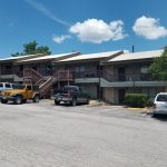 Apartment building with cars in parking lot.