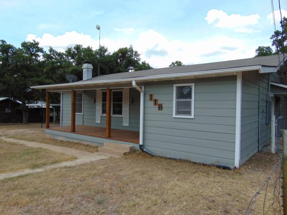Gray house with porch and wooden posts.