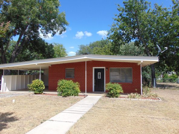 Brick ranch house with carport and lawn.