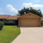 Tan brick house with attached garage.