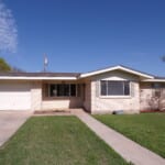 Ranch style house with yard and driveway.