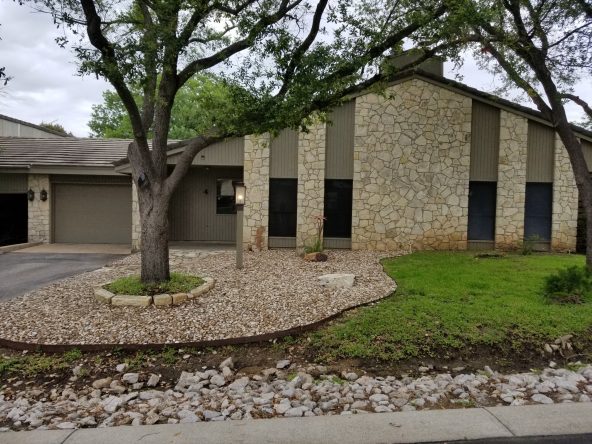 Stone house with green lawn and tree.