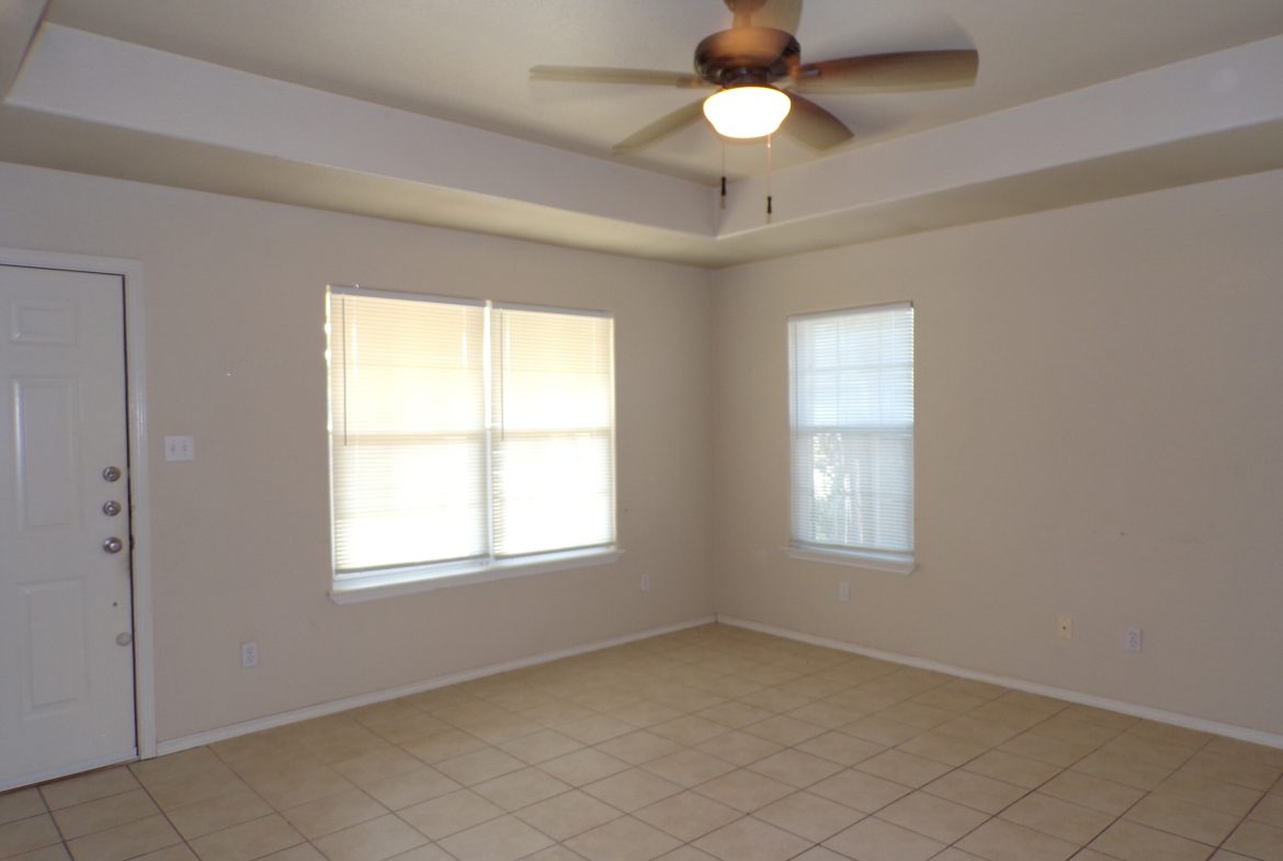 Empty room with ceiling fan and tile floor.