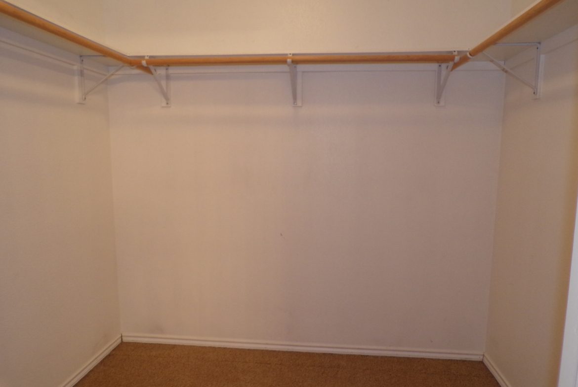 Empty closet with wood rod and shelf.