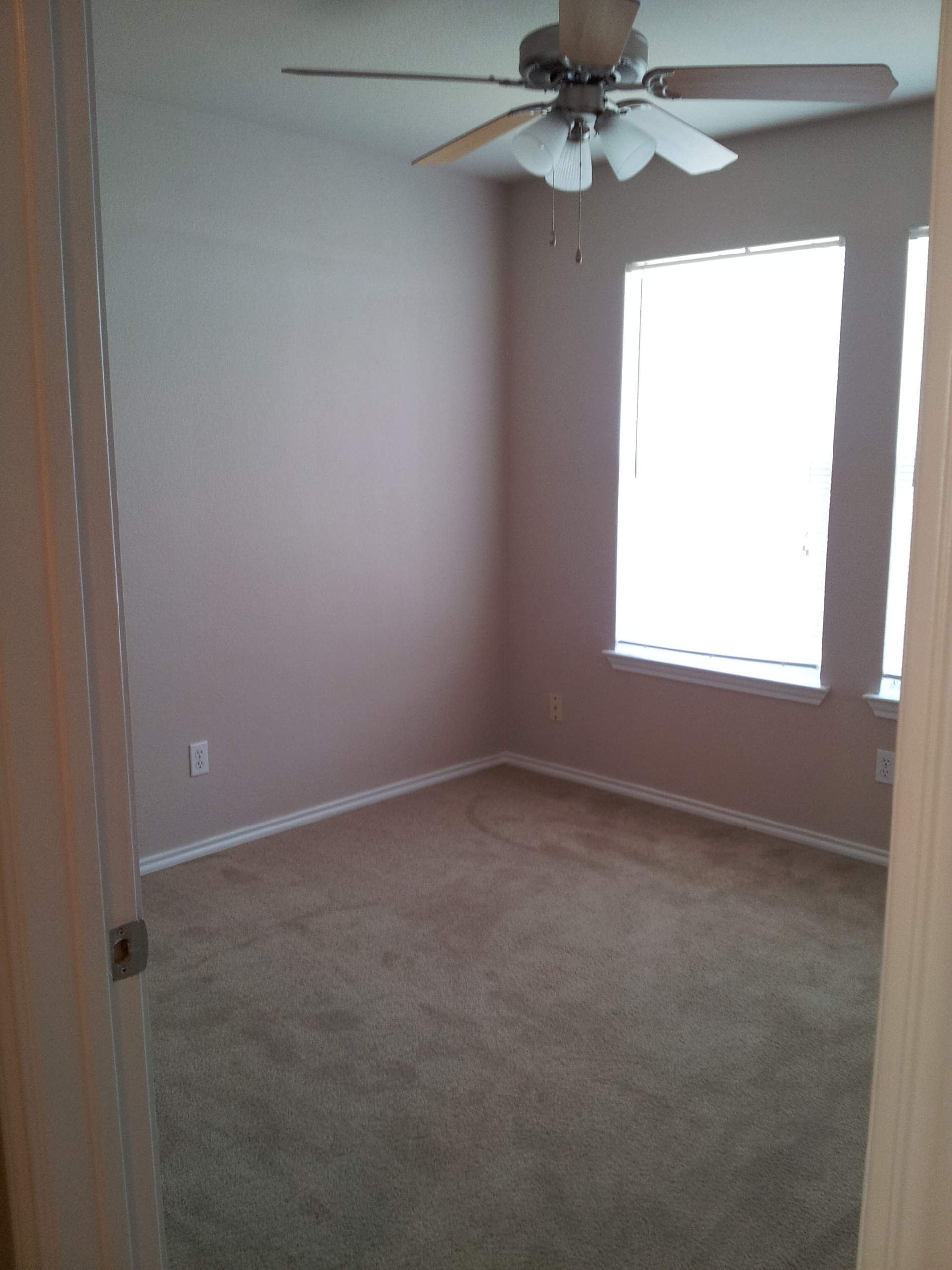 Empty carpeted bedroom with ceiling fan.