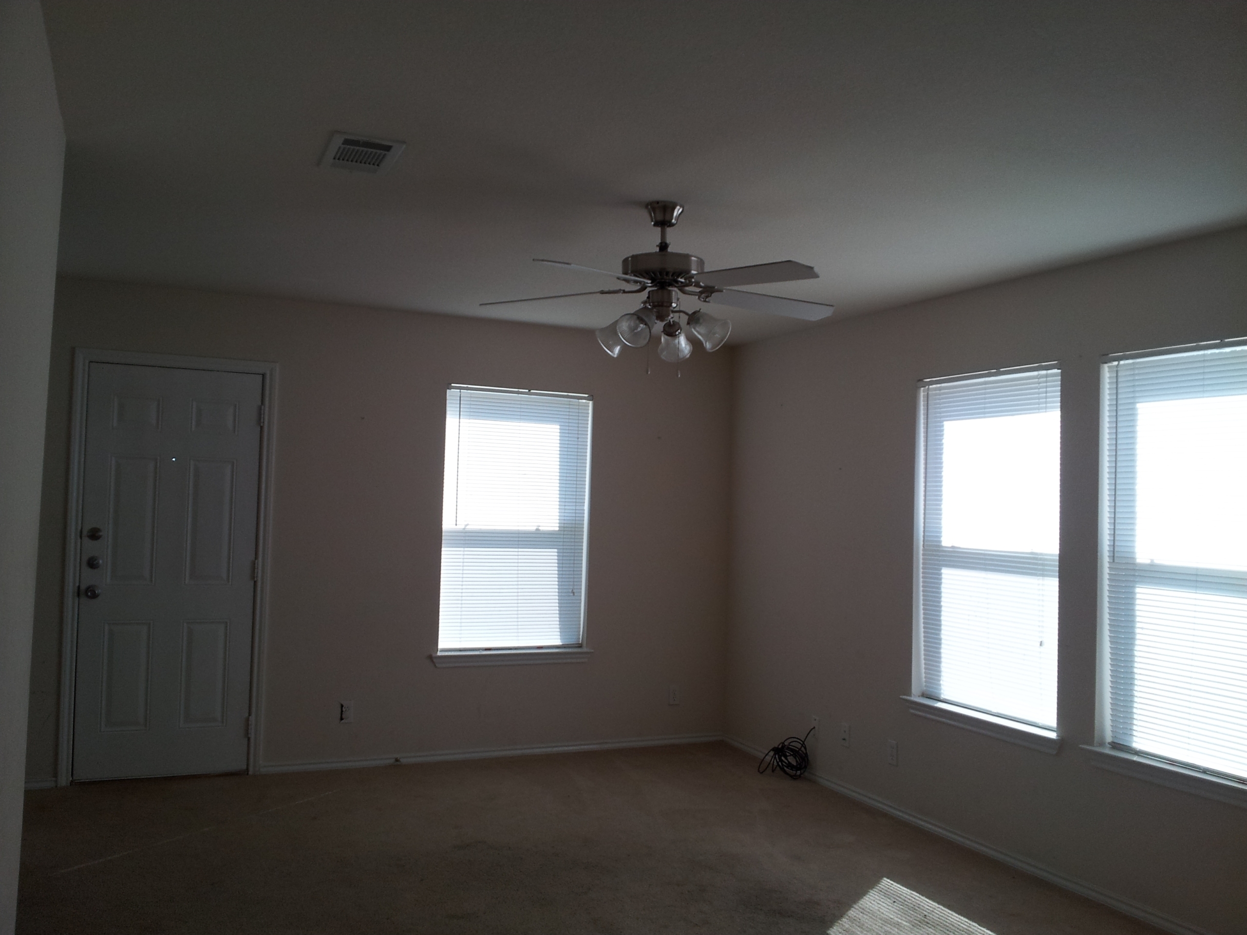 Empty room with ceiling fan and windows.
