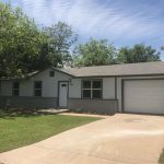 White house with garage and lawn.