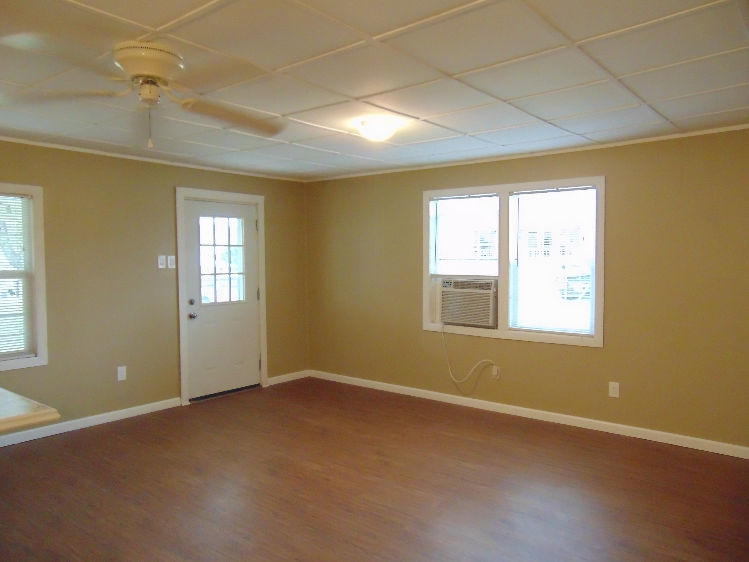 Empty room with wood floor, window, and door.