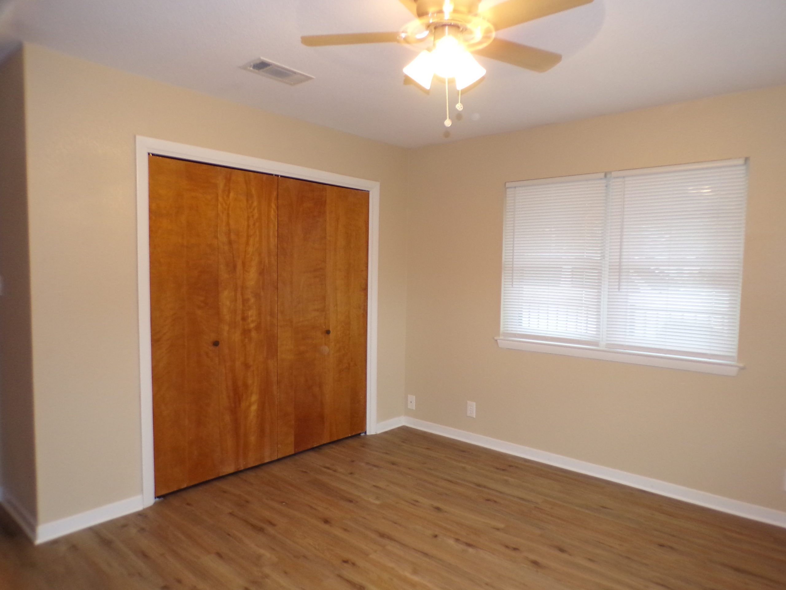 Empty bedroom with wood floors and closet.