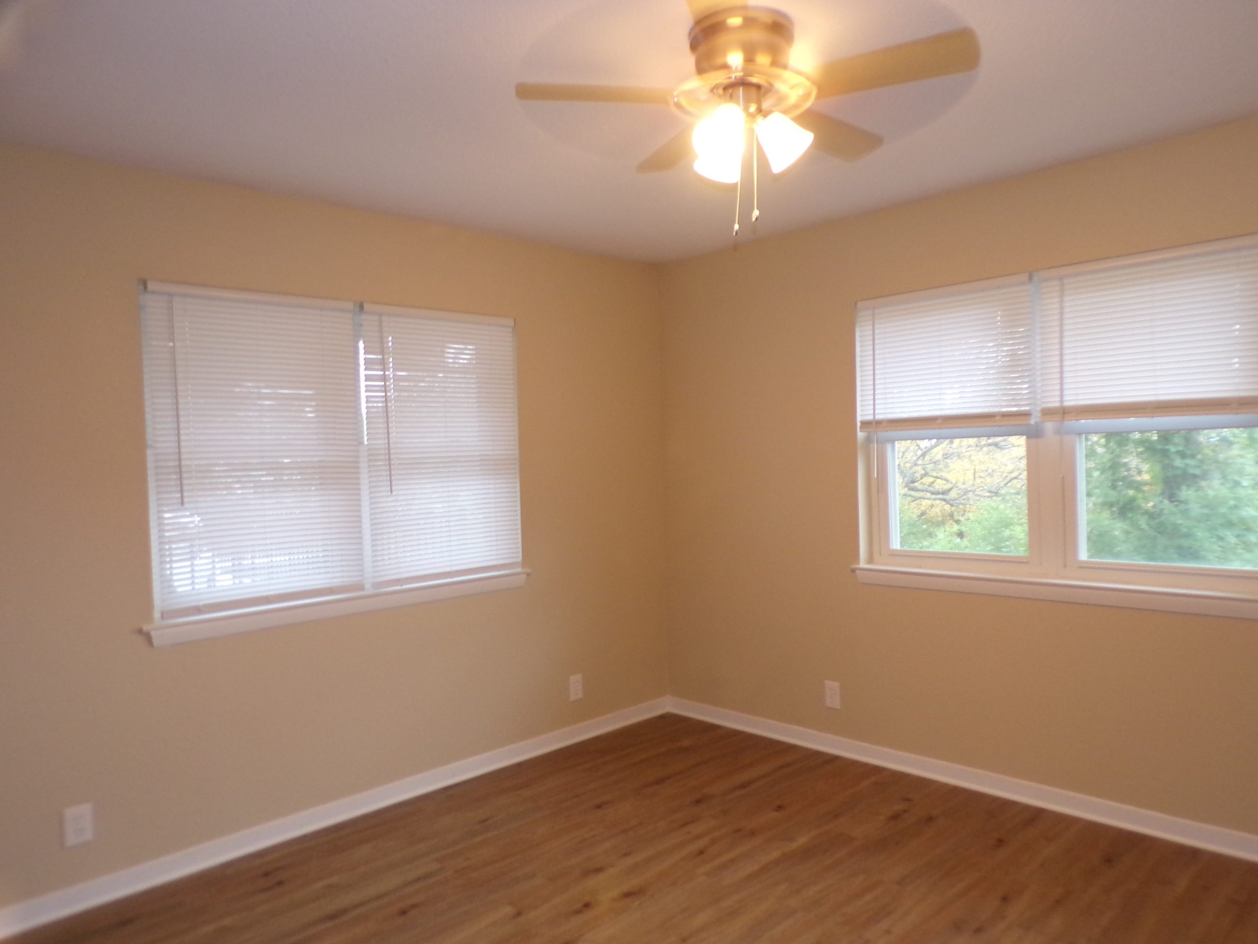Empty beige bedroom with wood floor.