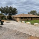 Gravel driveway and brick house.