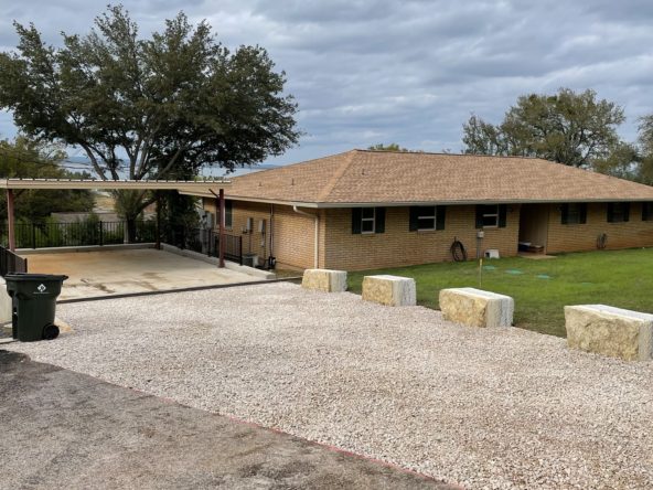Gravel driveway and brick house.