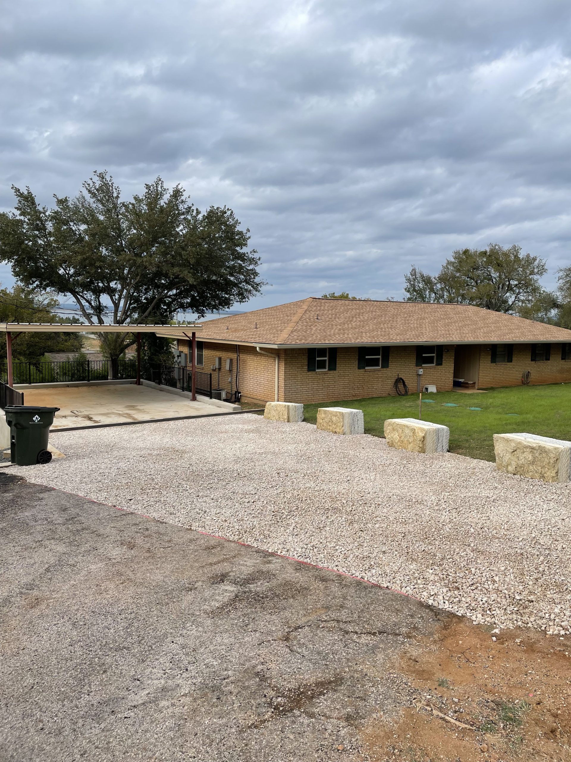 Gravel driveway and brick house.