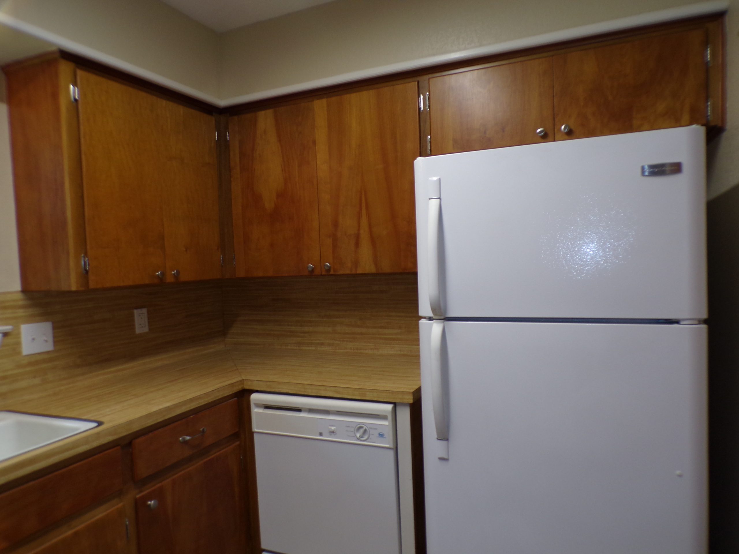 White refrigerator in kitchen with wood cabinets.