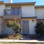 Tan stucco condo building, entrance.