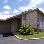 Stone house with yellow flowers and garage.