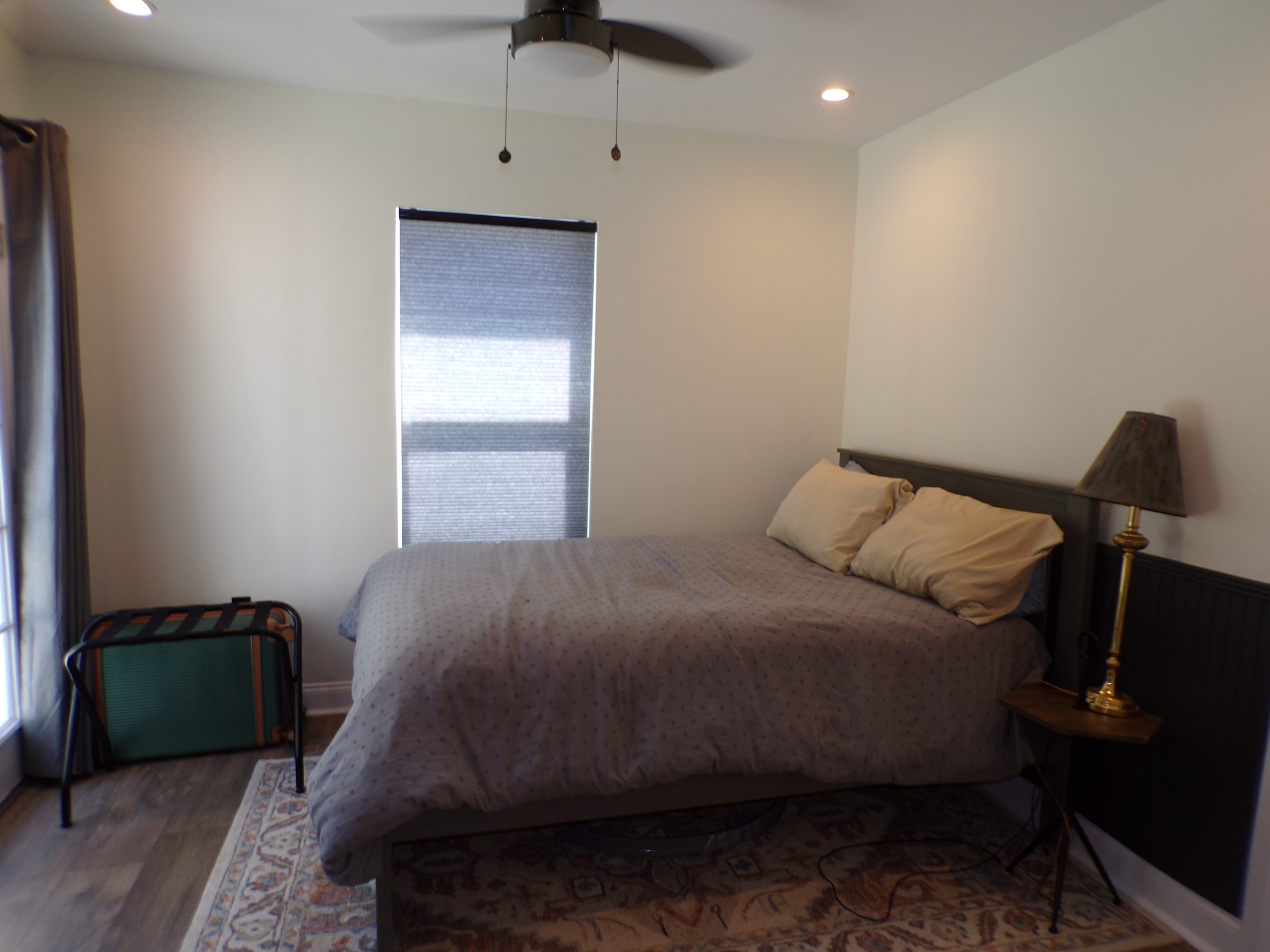 Bedroom with bed, ceiling fan, and luggage rack.