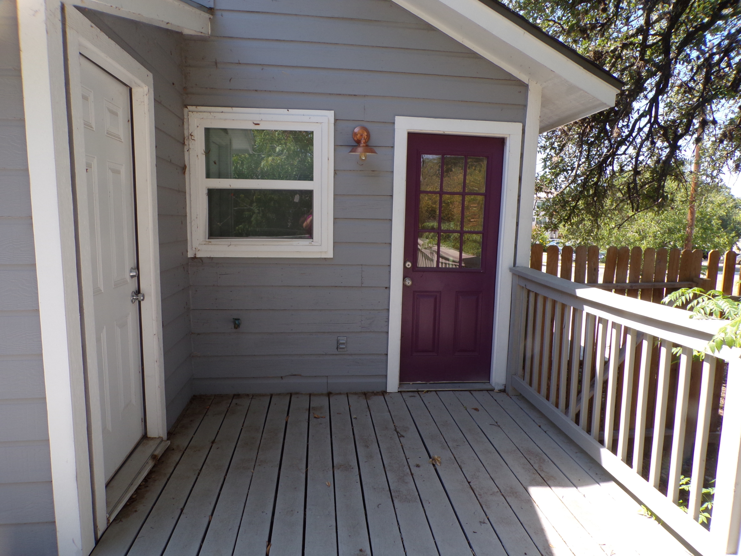 Gray house exterior with deck and doors.